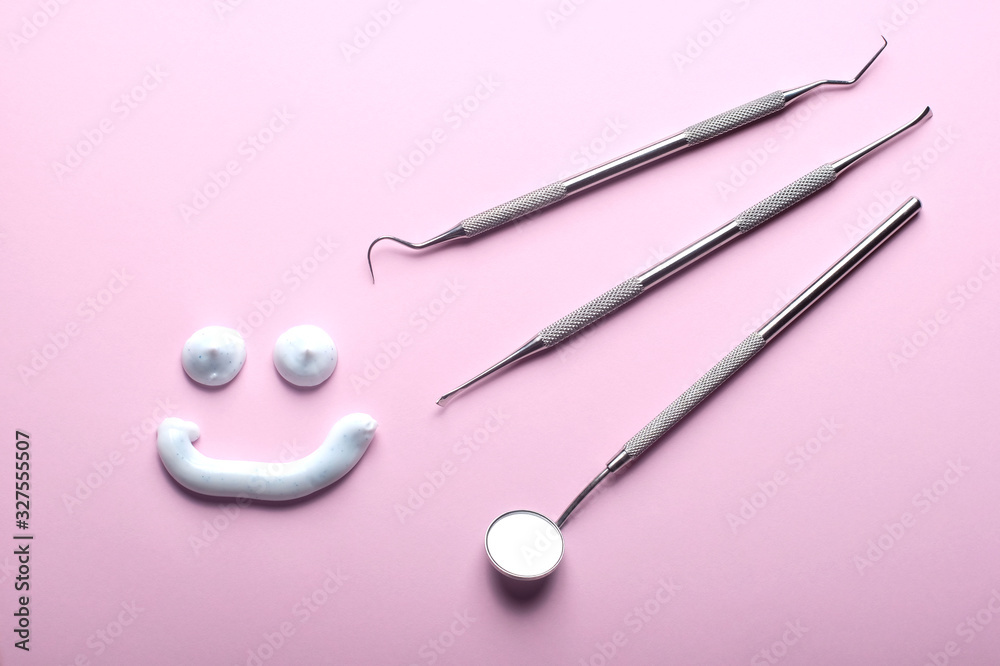 Stainless steel dental instruments and a toothpaste smiling face on pink background. Stainless steel dental instruments and a toothpaste smiling face on pink background.