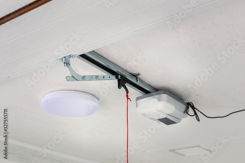 Fotografija Opening door and automatic garage door opener electric engine gear mounted on ceiling with emergency cord