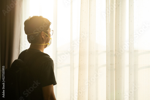 Traveller wearing surgical mask to prevent flu disease Coronavirus standing at the window at sunset photo