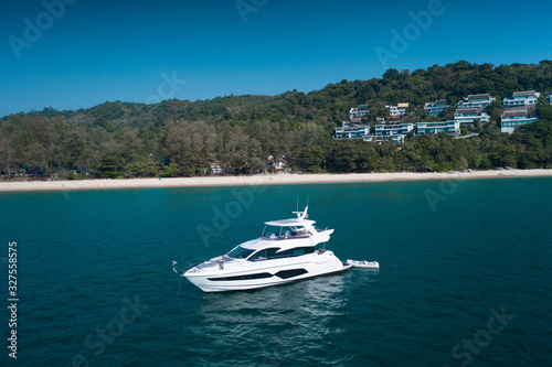 Aerial drone view of luxury white yacht in the blue sea with beach in the background. Travel concept