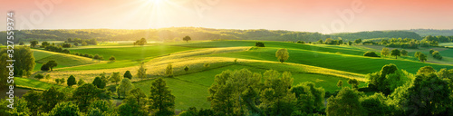 Valokuvatapetti Panoramic landscape with beautiful green hills and warm sunshine illuminating th