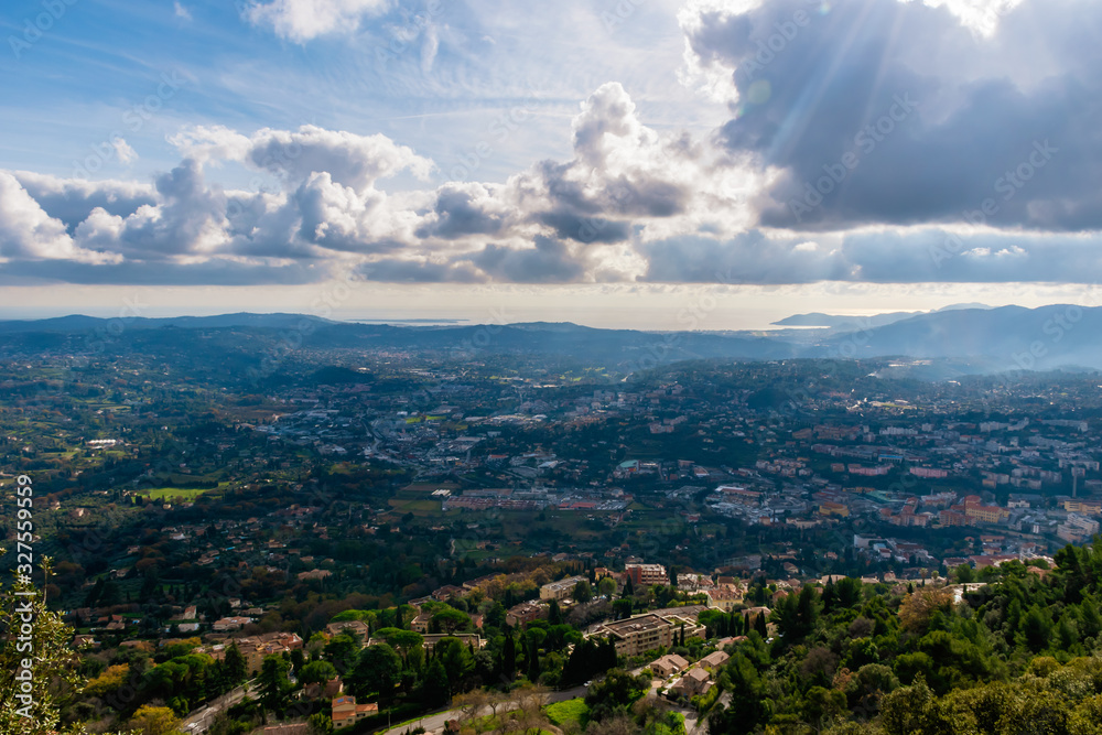 The panoramic view of a medieval French town in Côte d'Azur under the cloudy sky and the Meditarrenean sea coastline in the horizon