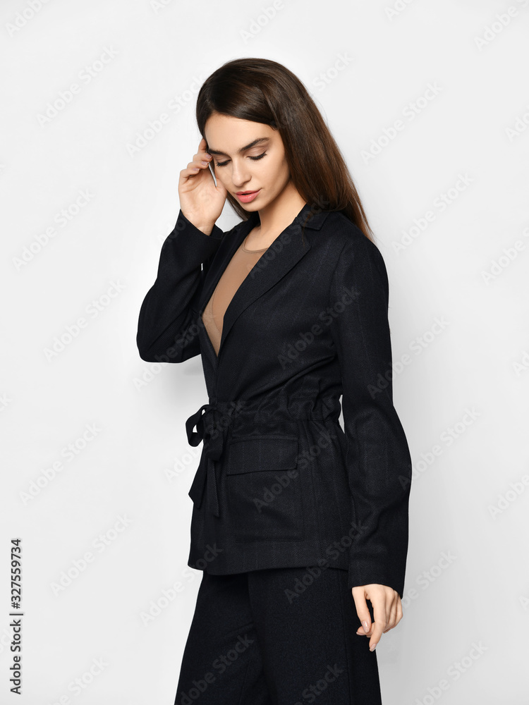 Young beautiful brunette woman in stylish pantsuit pajama is walking passing by looking down over grey background