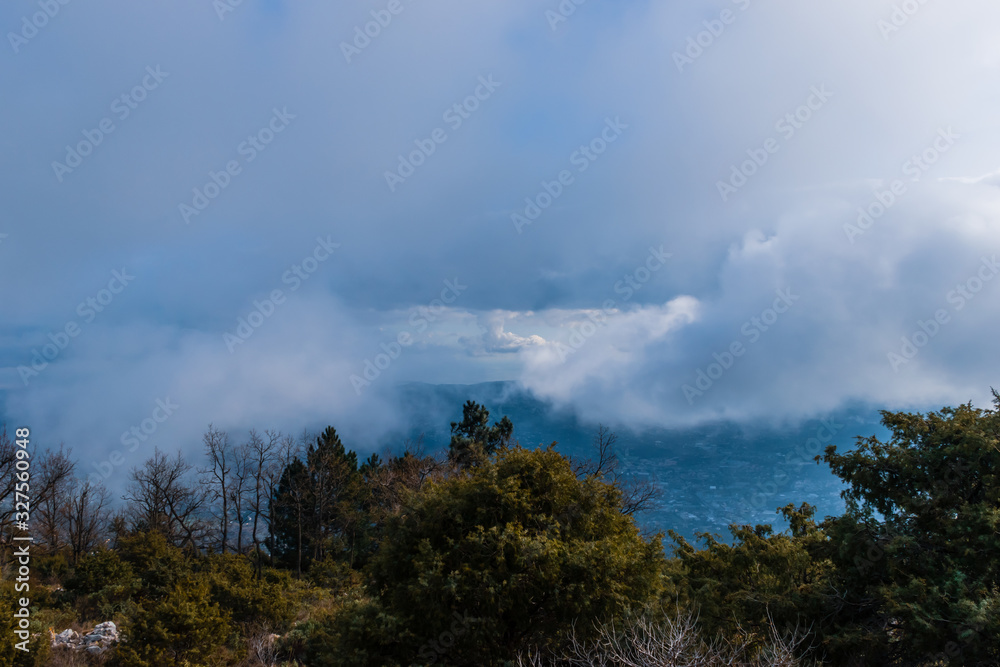 The panoramic view of Côte d'Azur Alps mountains under the cloudy sky and the Meditarrenean sea coastline in the horizon