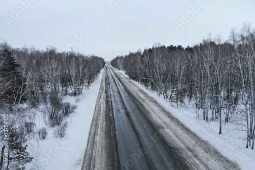 Aerial view of a car on winter road in the forest. Winter landscape countryside. Aerial photography of snowy forest with car on the road. Captured from above with a drone © Torkhov