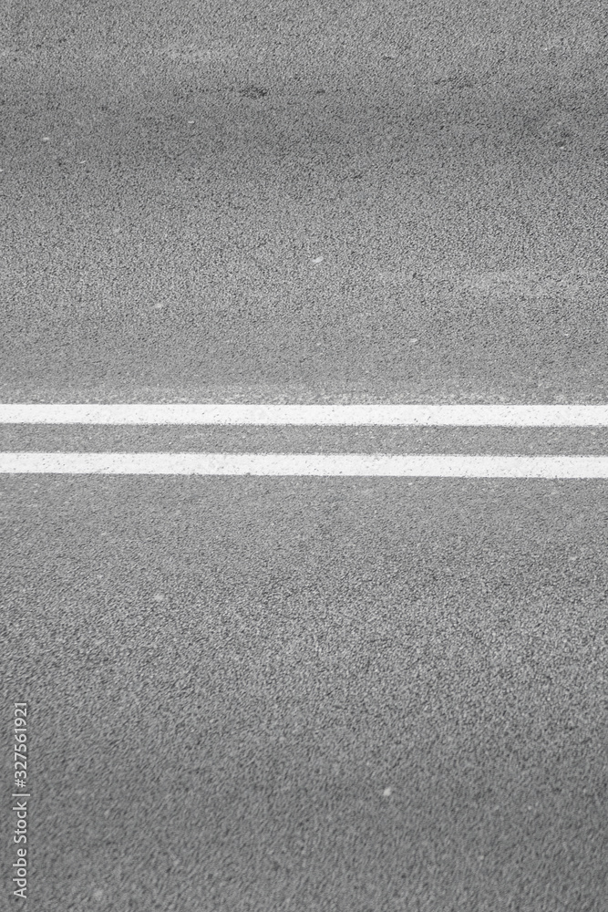 close-up of a road with continuous lines painted white horizontally