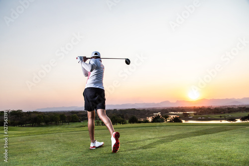 Professinal golf player on golf course. Pro golfer taking a shot at the sunset
