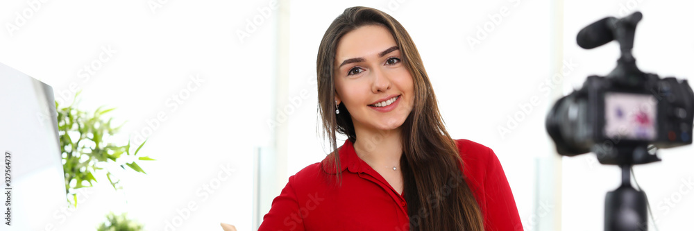 Young woman sitting in office opposite camera on tripod Young woman sitting in office opposite camera on tripod
