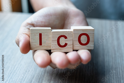 Businessman hand holding ICO (Initial Coin Offering) word with wooden cube block, is the cryptocurrency industry equivalent to an Initial Public Offering (IPO). Stock, Fund, Investors and Investment