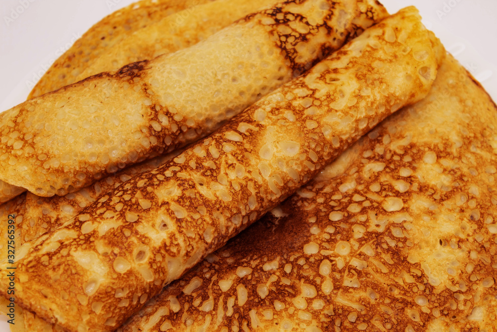 Fresh fried thin round pancakes close up on a light background