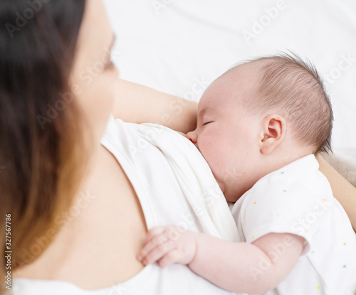 Young mother breast feeding her newborn son in her arms at home