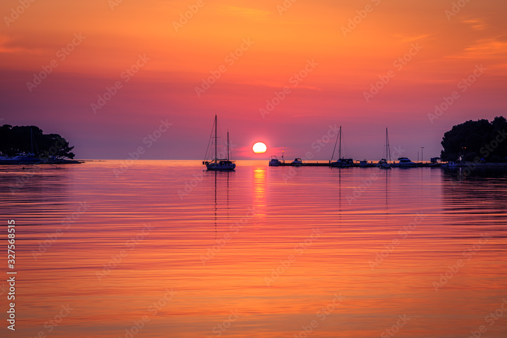 Sunset with boat silhouettes on the Adriatic sea. The Green lagoon in Porec - Istria, Croatia, Europe.
