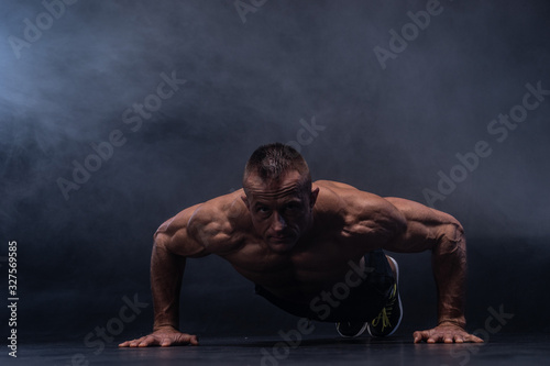Muscular man doing calisthenic exercise isolated on the black background