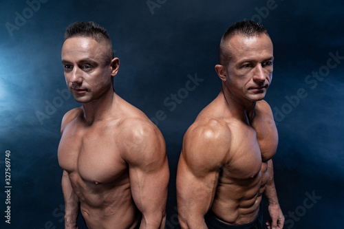 Two Muscular man isolated on the black background. Strong male naked torso abs