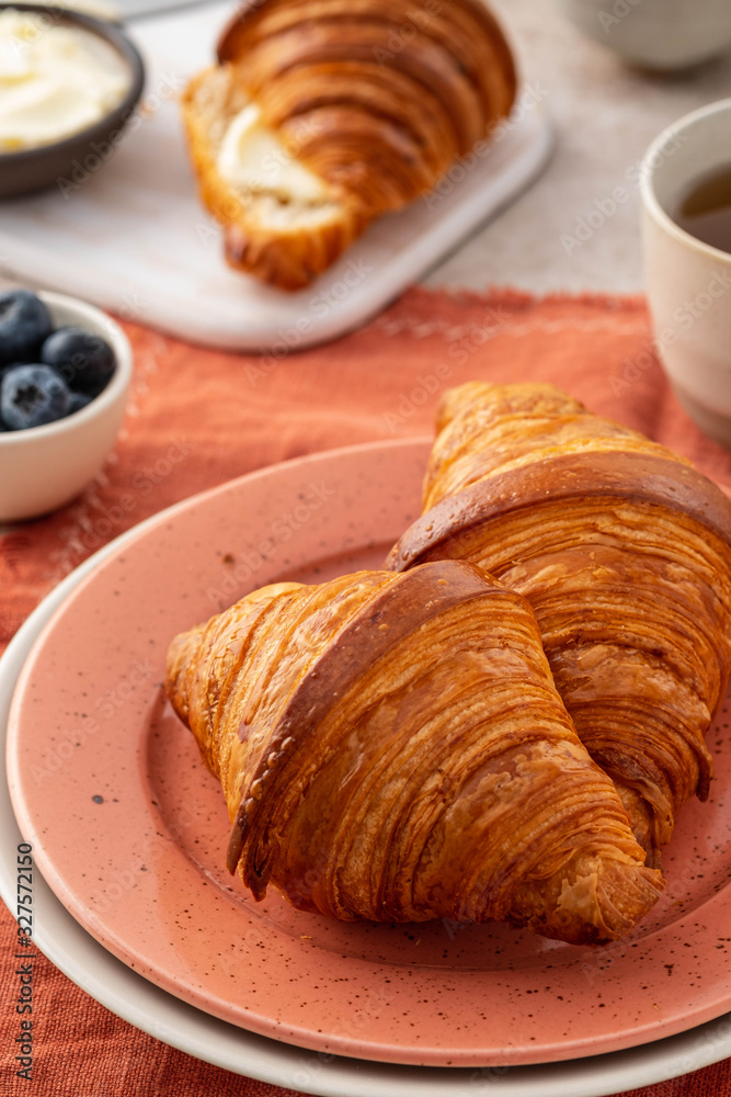 Fresh croissants with blueberries and honey, gray background.