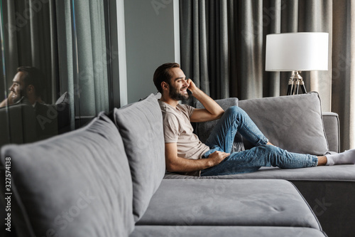 Optimistic young man indoors at home on sofa photo
