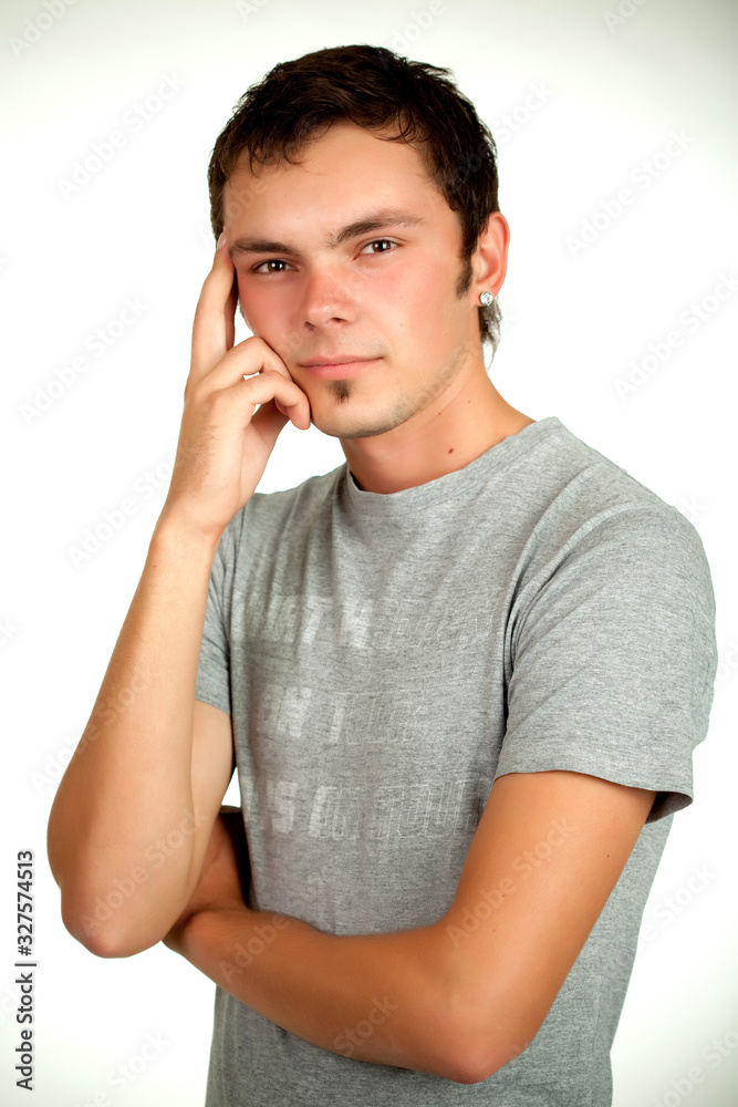 Portrait of a Caucasian young positive guy in a gray shirt and jeans posing on a gray background. Concept of a successful young student or novice employee. Advertising space Portrait of a Caucasian young positive guy in a gray shirt and jeans posing on a gray background. Concept of a successful young student or novice employee. Advertising space