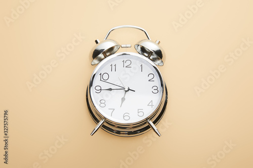 top view of classic alarm clock on beige background