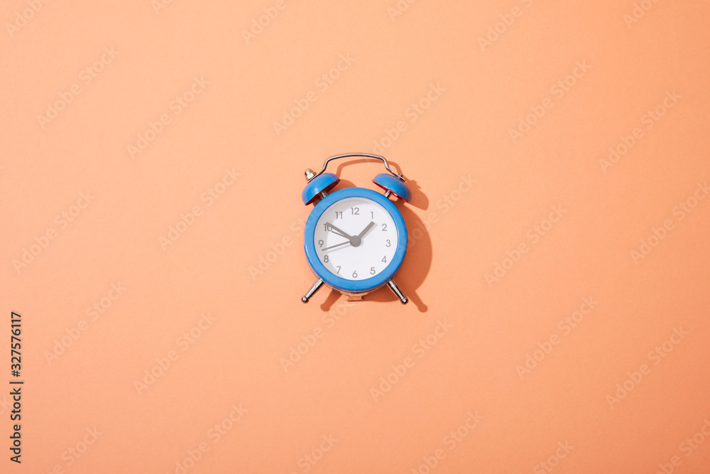 top view of classic alarm clock on peach background top view of classic alarm clock on peach background
