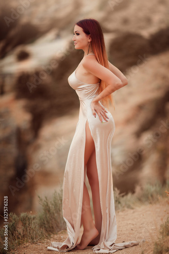 Beautiful young girl stands on a cliff of rock