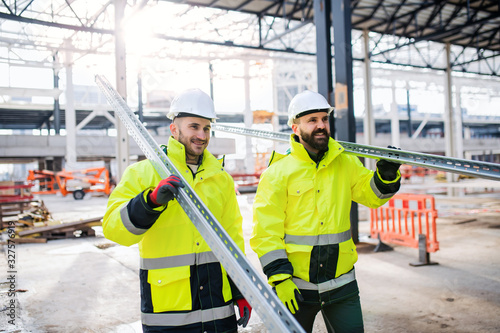 Men workers walking outdoors on construction site, working. photo