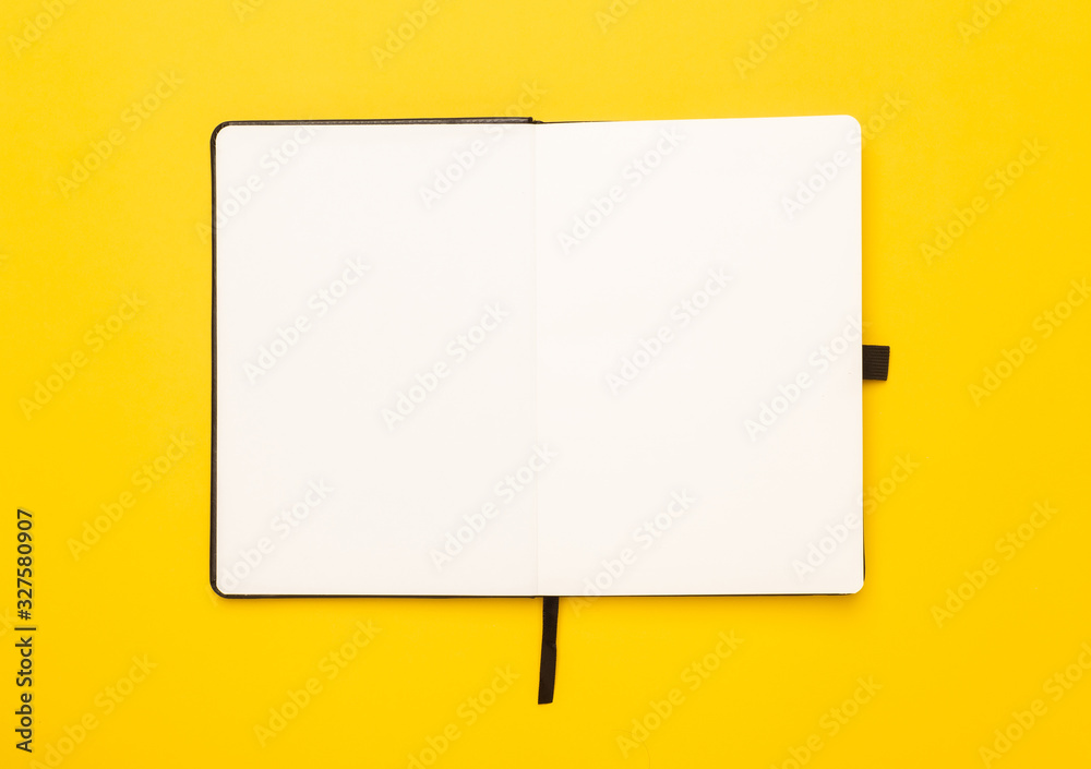 Black notebook opened isolated on yellow background. Black notebook opened isolated on yellow background.
