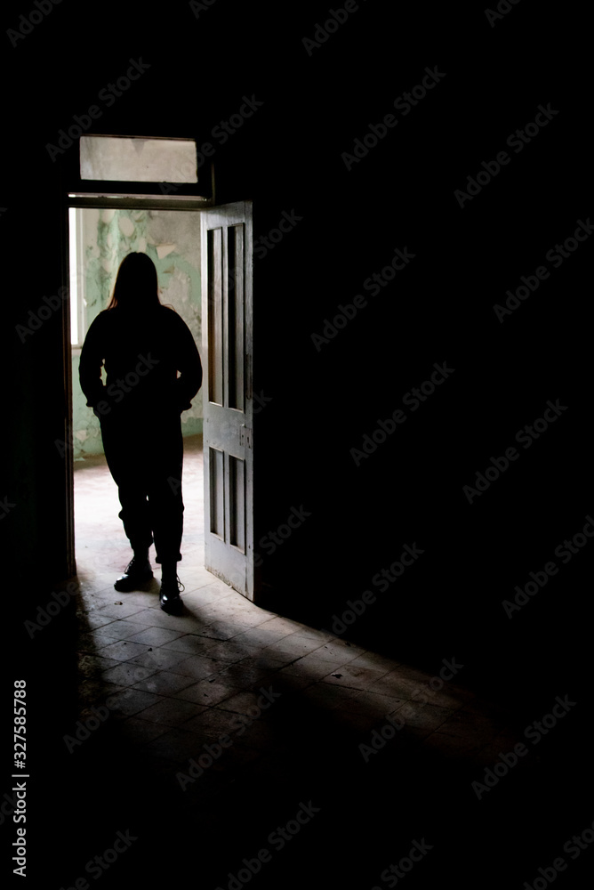 Unrecognised person standing alone on the open door of an abandoned building