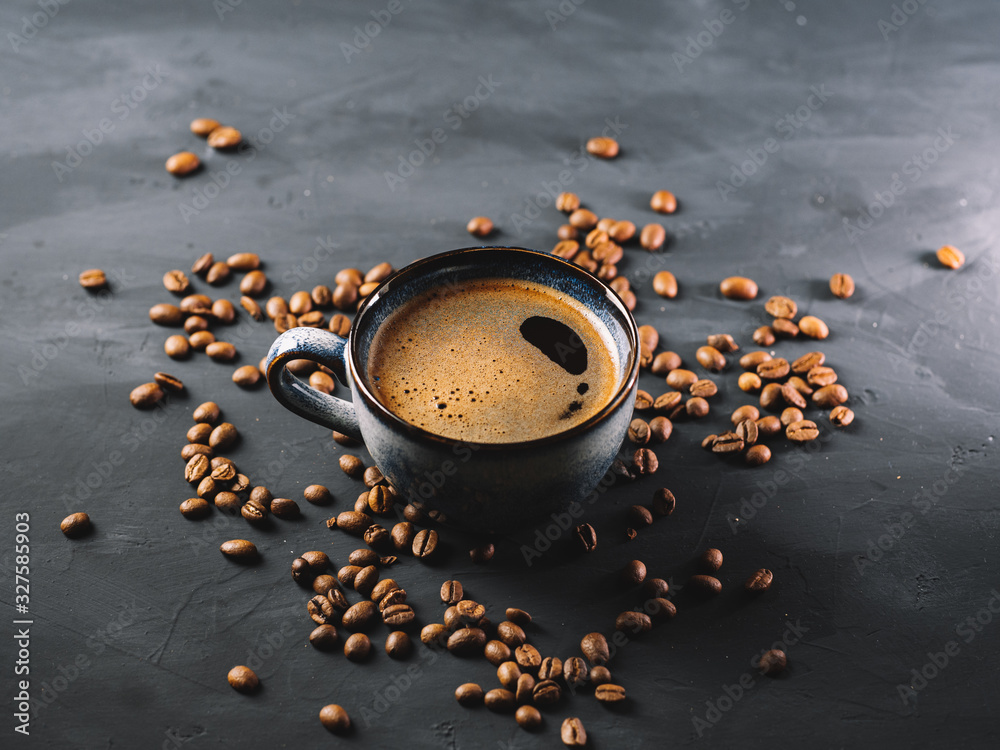 Keuken achterwand met A Cup of hot aromatic espresso coffee on a stone table with scattered roasted coffee beans #327585903