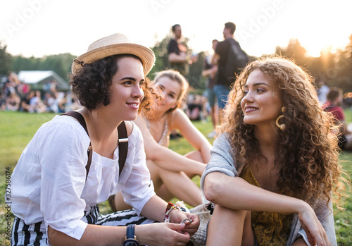 Group of young female friends sitting on ground at summer festival.