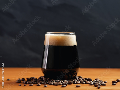 Foto Craft beer coffee stout in a glass on a wooden table