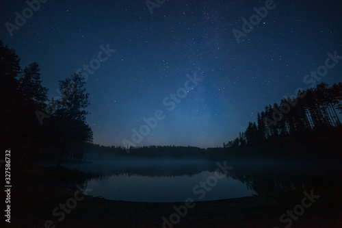 one million stars over the lake during sunrise. long exposure. Trail from a flying satellite. Milky way
