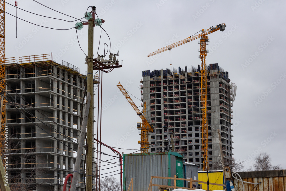 building at a construction site made of reinforced concrete frame with a crane against a gray sky building at a construction site made of reinforced concrete frame with a crane against a gray sky