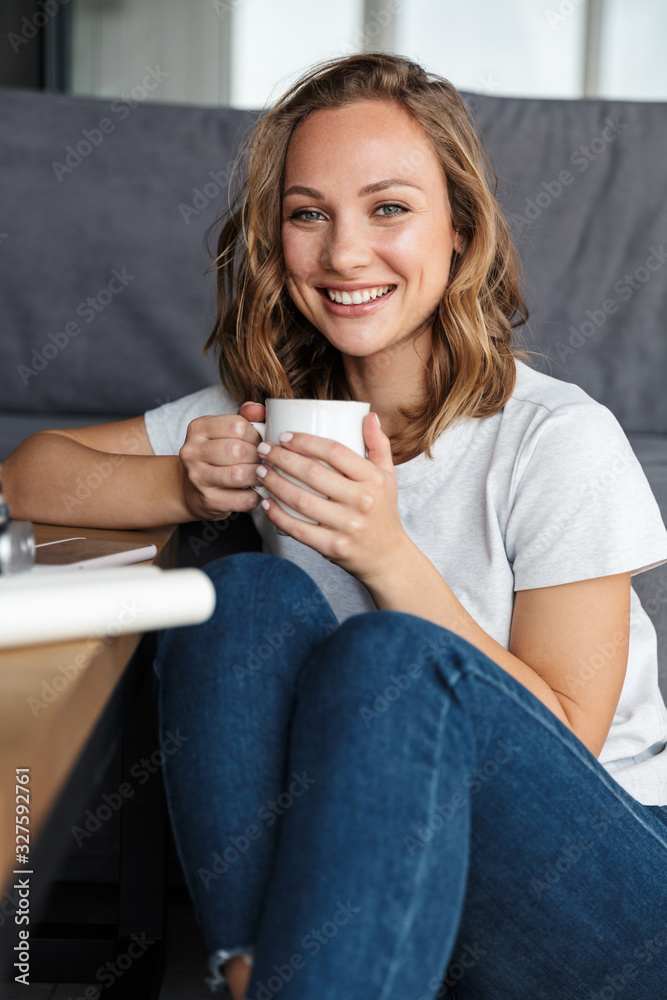 Image of happy attractive woman smiling and drinking coffee