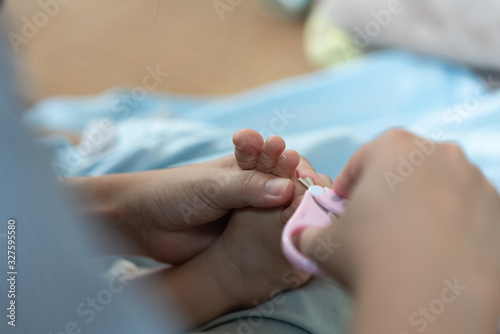The mother took the scissors and cut the toenails for the child