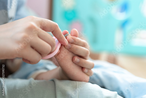 The mother took the scissors and cut the toenails for the child