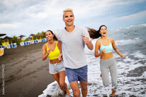 Group of athletes running on ocean front. Friends in sportswear training together outdoors.
