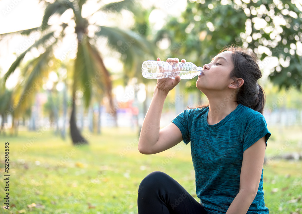 Asian woman drinking water after exercising at the park Asian woman drinking water after exercising at the park