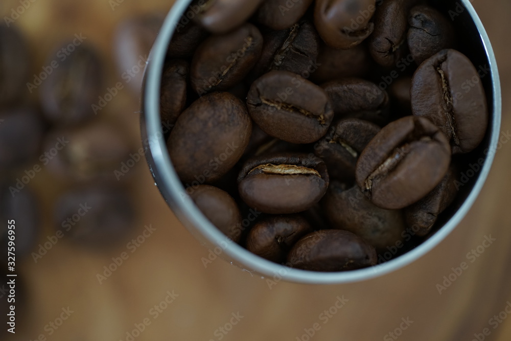 Fototapeta premium Kaffeebohnen in einem Kaffeedosierlöffel auf einem Holzbrett
