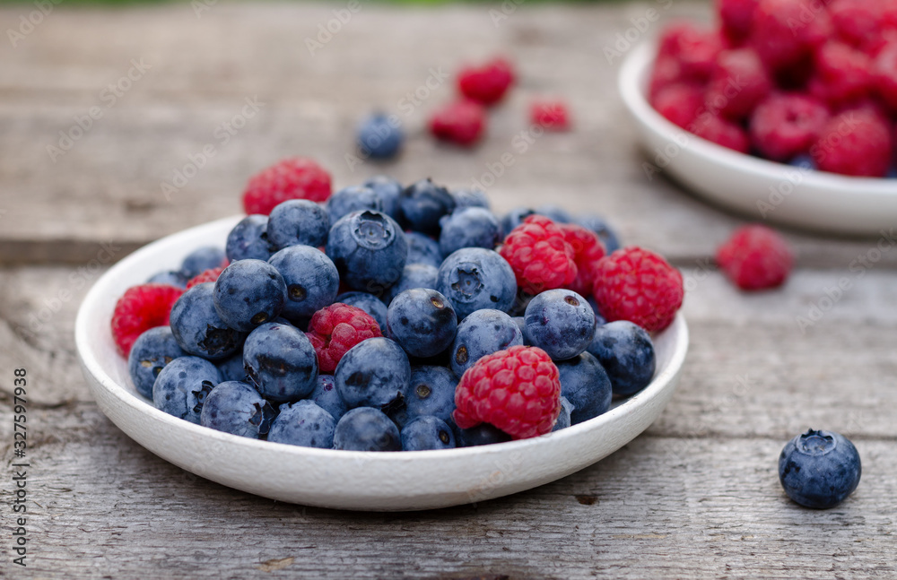 Still life with a blueberries and raspberries on an old wooden table, at the garden. Rural natural food style.
