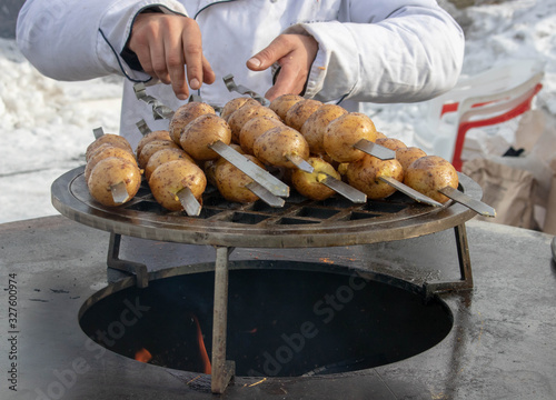 Grilled fresh potato tubers strung on skewers photo