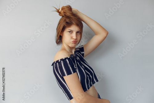 Beautiful girl in a studio. Stylish girl near blue wall. Lady shows her emotions/