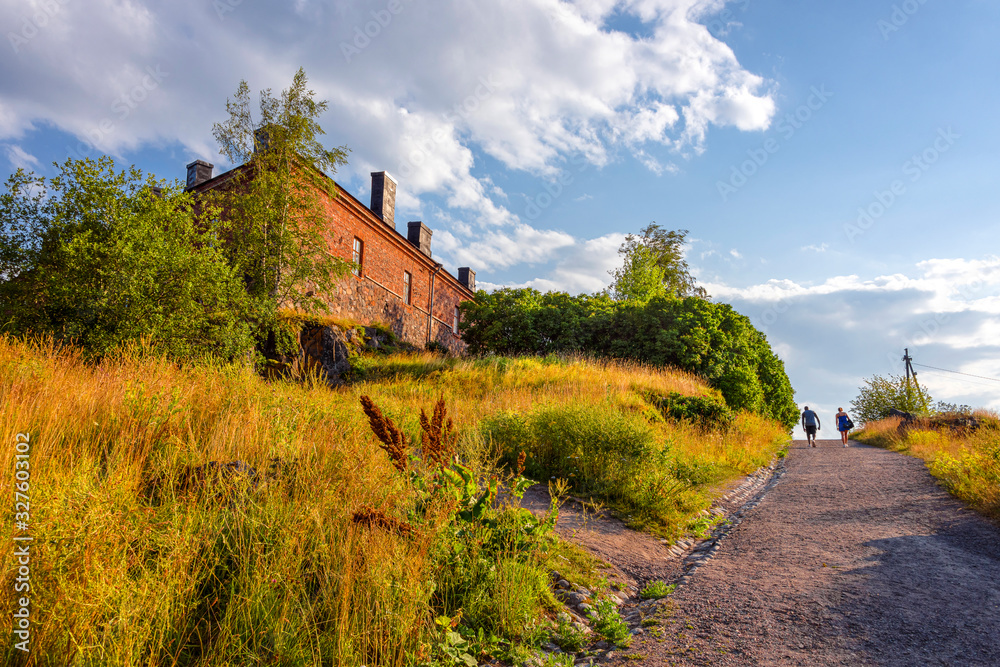 Finland, Sveaborg, Suomenlinna: Romantic sunny afternoon scene in the center of the famous Finnish island with old building, yellow grass meadow, blue sky - concept travel sunset nature vacation