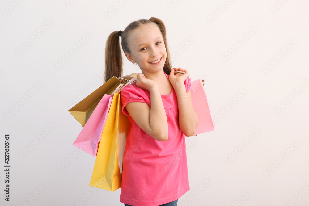 Beautiful smiling little girl with bags for shopping on a colored background. The concept of children's shopping. Beautiful smiling little girl with bags for shopping on a colored background. The concept of children's shopping.