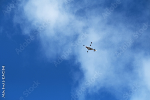 A seaside nautical search and rescue helicopter with rotating blades in the distance with a vivid bright blue sky and clouds. Rescue helicopter and rescue teams are brave.
