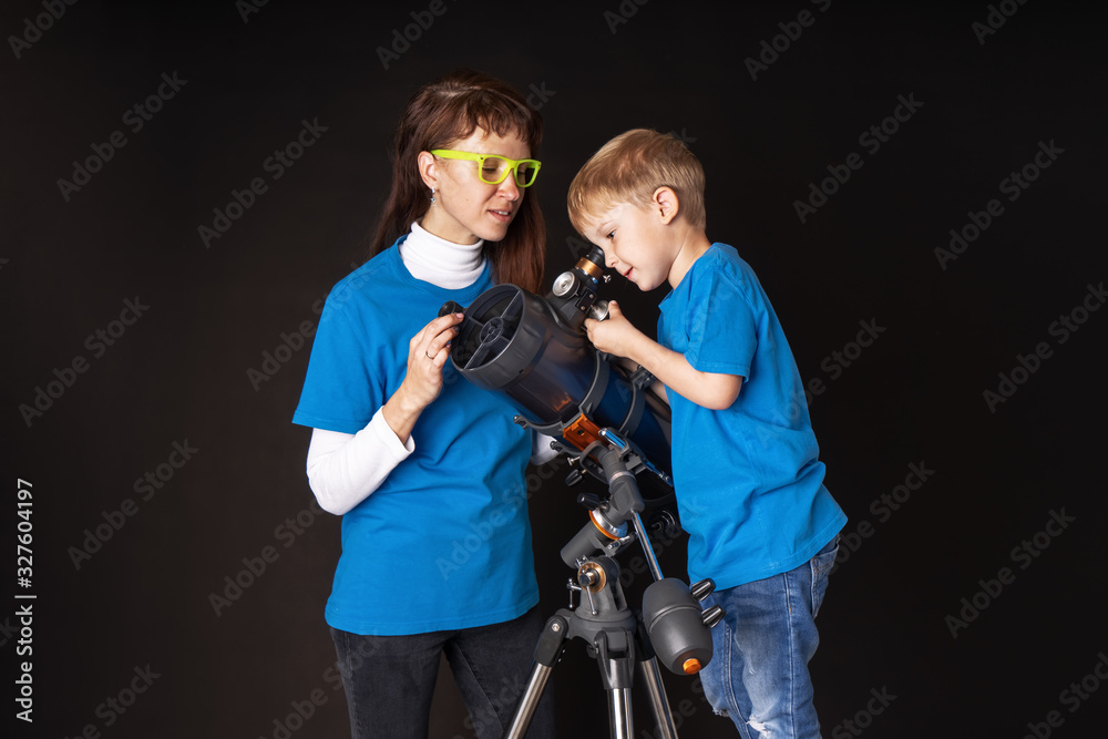 Mom and son are studying a large refractory telescope.