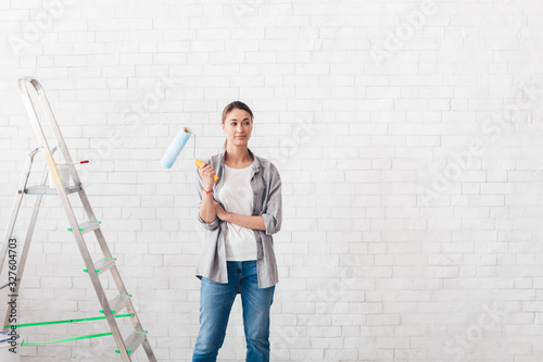 Young woman holding a roller for painting walls in new house