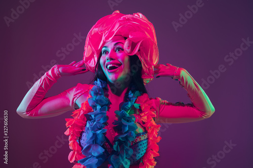Beauty. Hawaiian brunette model on purple studio background in neon light. Beautiful women in traditional clothes smiling, dancing and having fun. Bright holiday's, celebration colors, festival.