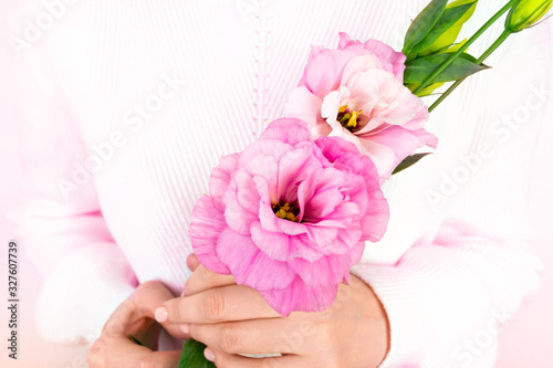 Beautiful woman s hands with nude manicure hold eustoma purple flower. White sweater. Pink blooming spring plant