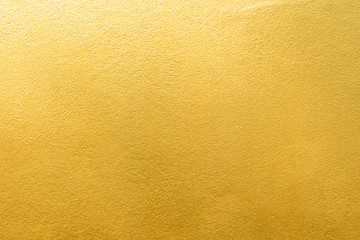 Gold wall texture background. Yellow shiny gold foil paint on wall surface with light reflection