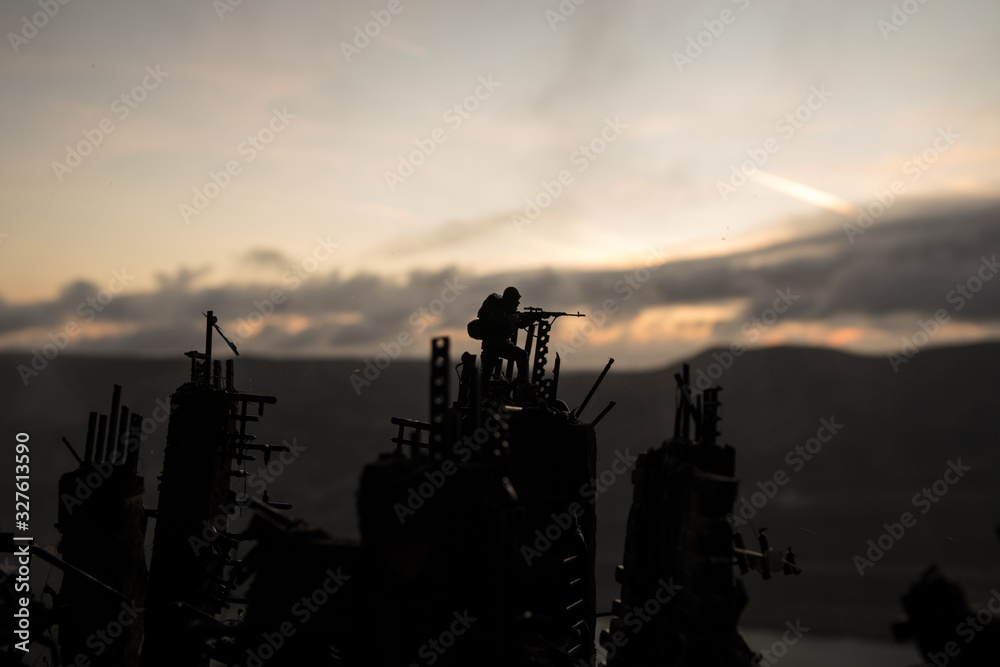 Army sniper with large caliber rifle standing in the fire and smoke. War Concept. Battle scene on war fog sky background, Fighting silhouettes Below Cloudy Skyline at night. City destroyed by war Army sniper with large caliber rifle standing in the fire and smoke. War Concept. Battle scene on war fog sky background, Fighting silhouettes Below Cloudy Skyline at night. City destroyed by war
